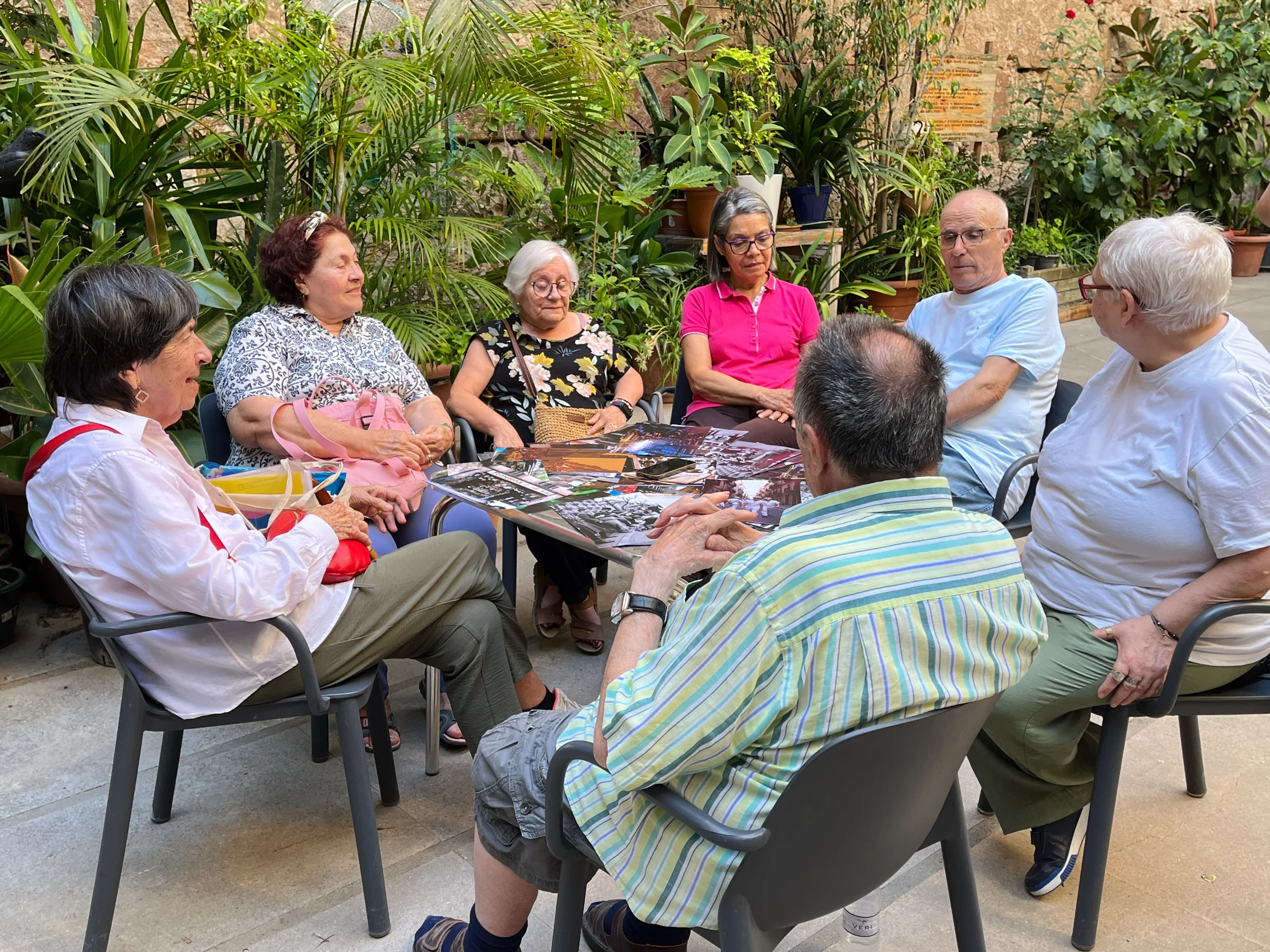 Older adults sitting together in a courtyard, looking through photographs